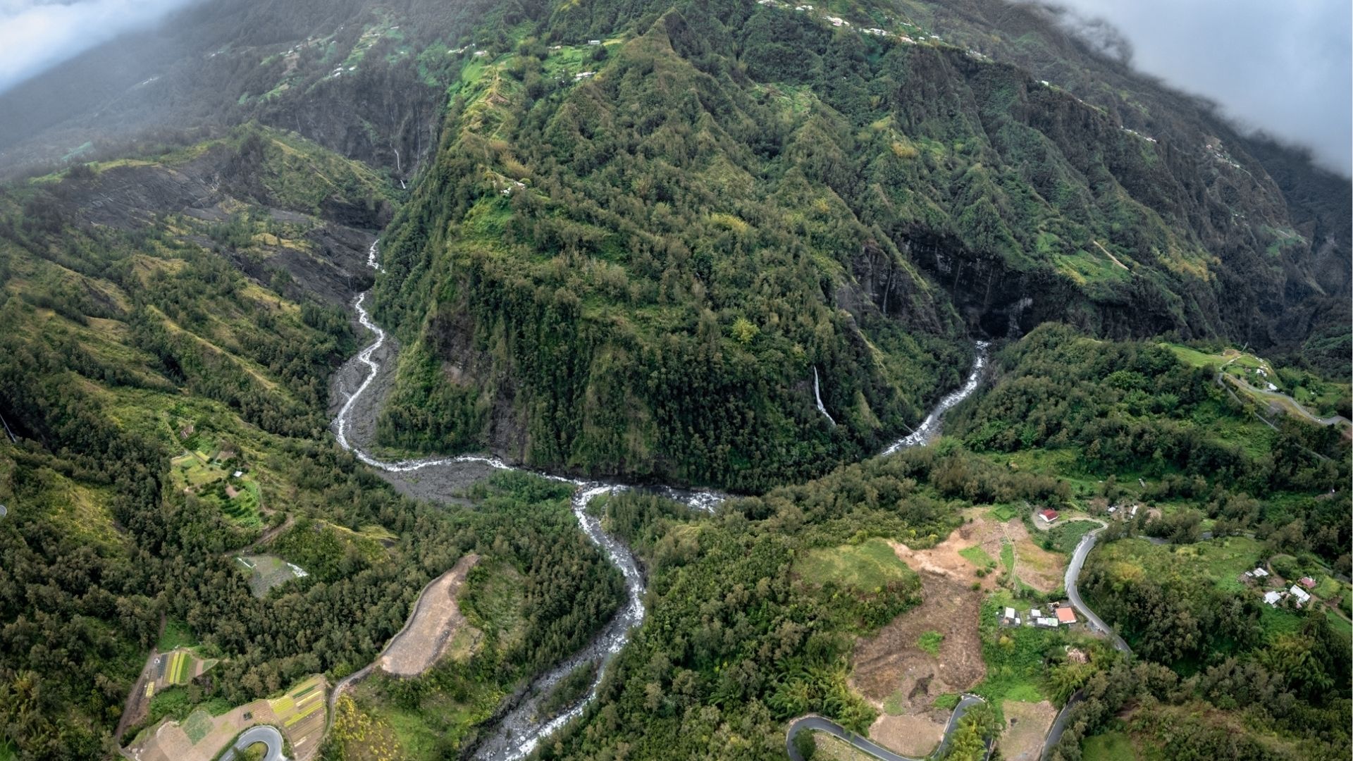 Rivière serpentant à travers une montagne luxuriante, avec végétation dense et paysages verdoyants de La Réunion