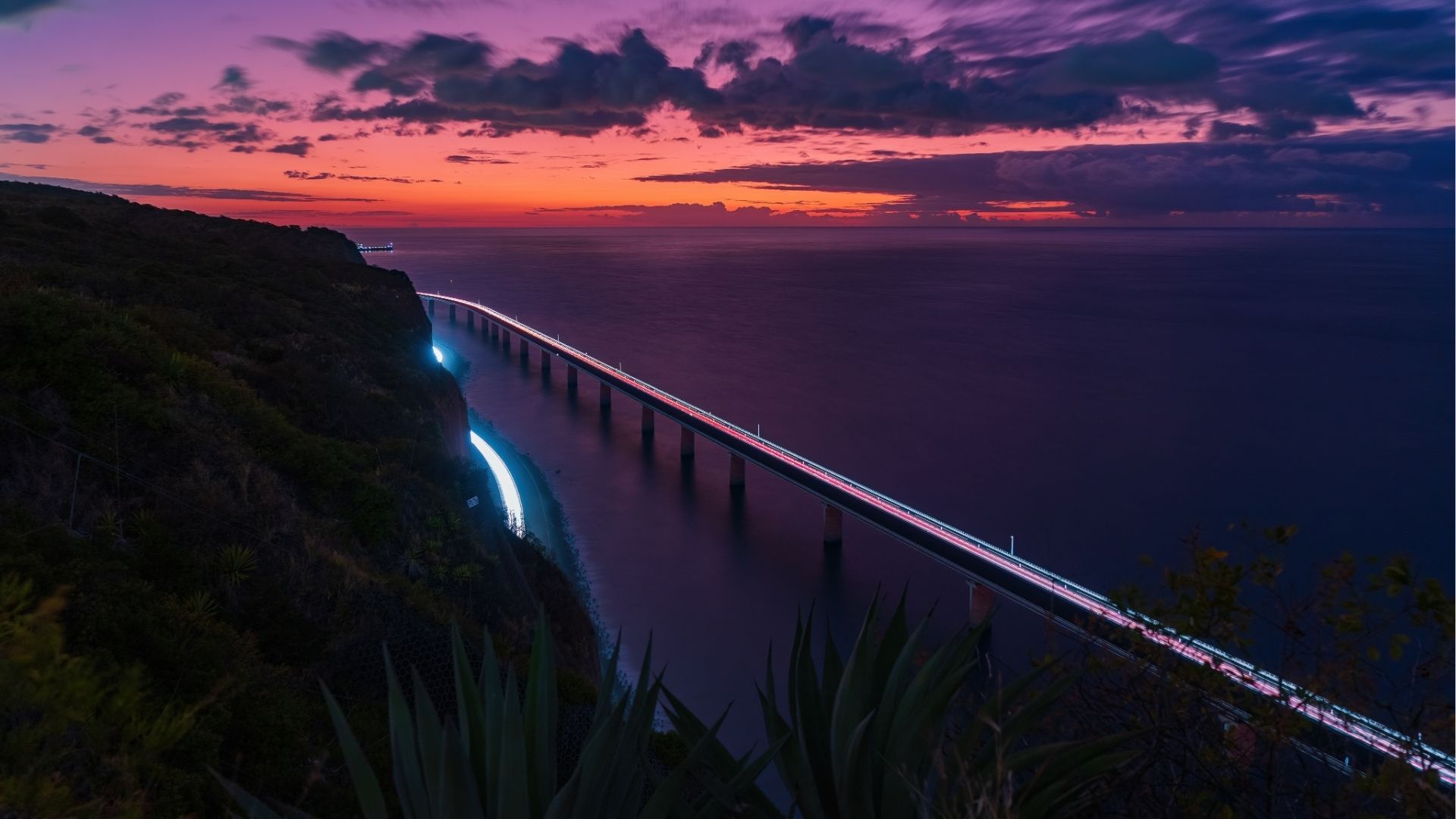 Vue nocturne de la Nouvelle Route du Littoral près de Saint-Denis avec les lumières des voitures au coucher du soleil
