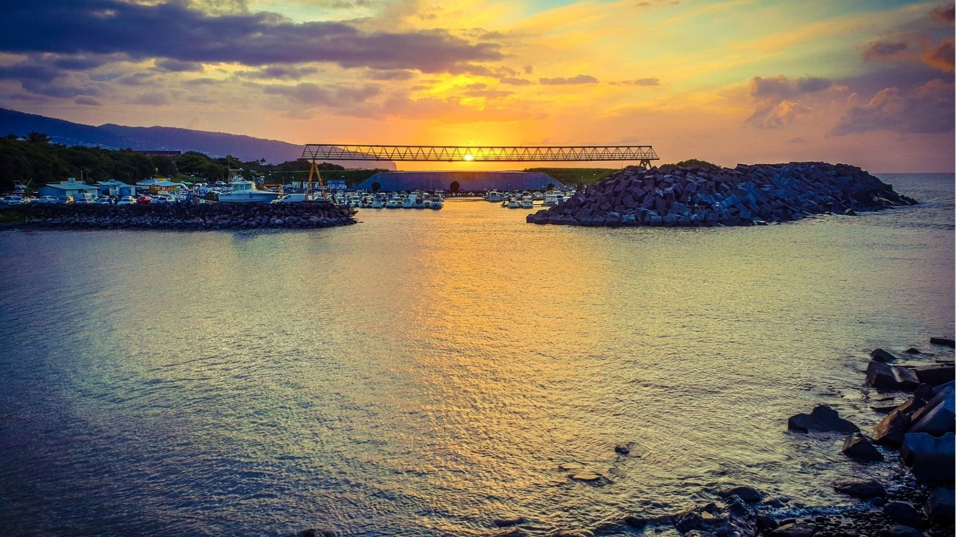 Coucher de soleil sur le port de Sainte-Marie avec reflets dorés sur l’océan à La Réunion