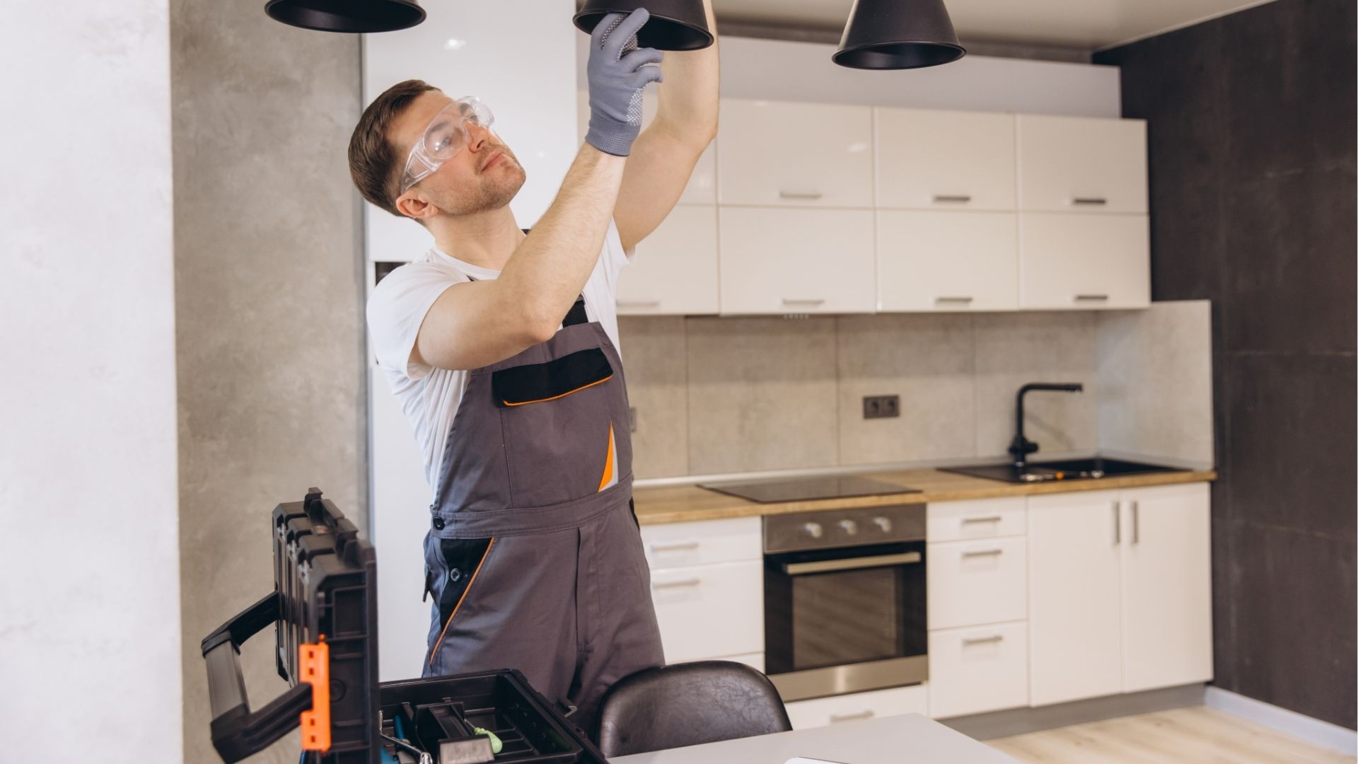 électricien installant un luminaire dans une cuisine moderne