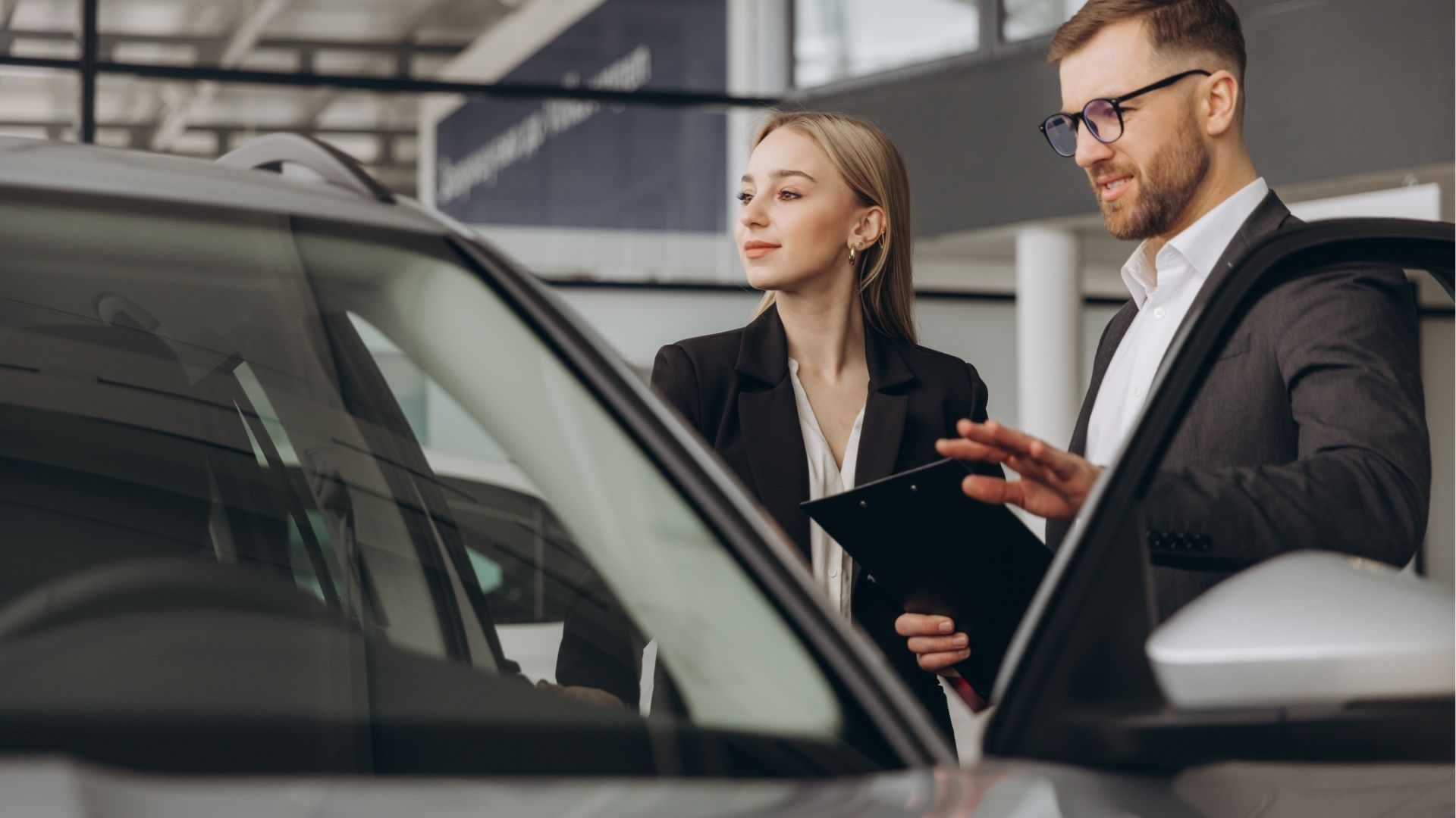 conseiller automobile présentant un véhicule à une cliente dans un showroom