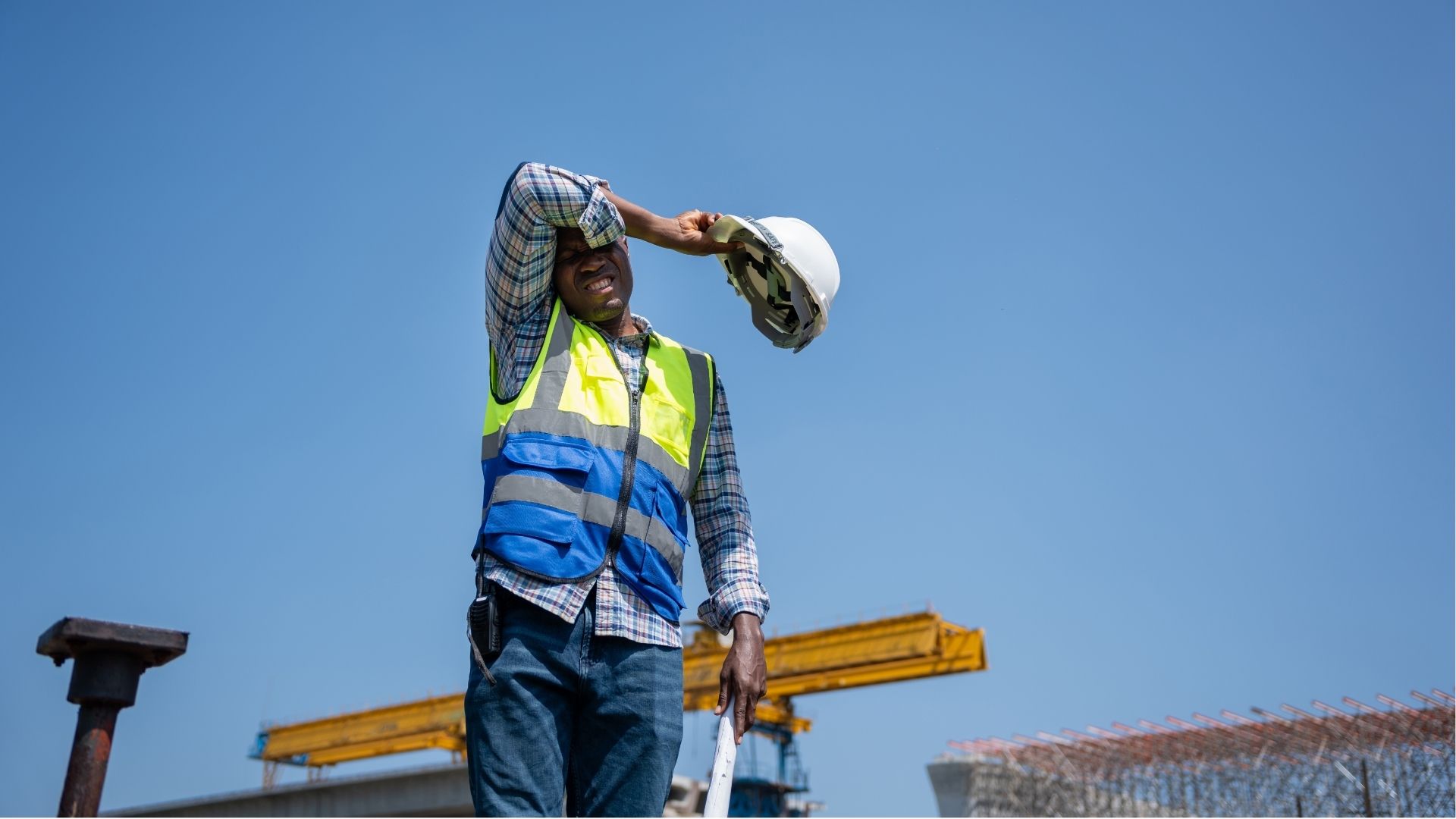 ouvrier de chantier retirant son casque sous le soleil