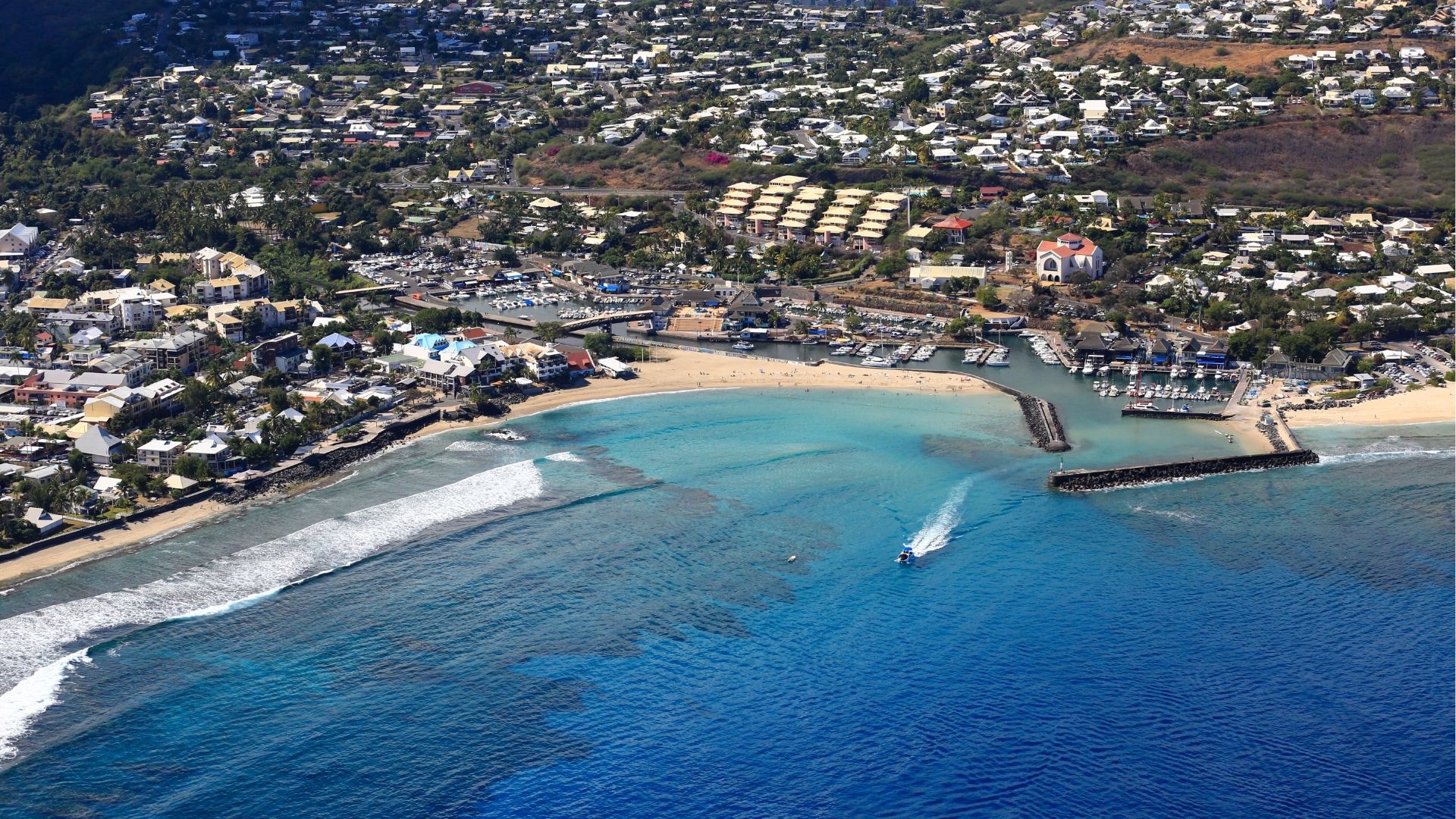 vue aérienne du port de Saint-Gilles-les-Bains avec la plage, la barrière de corail et la ville en arrière-plan à La Réunion